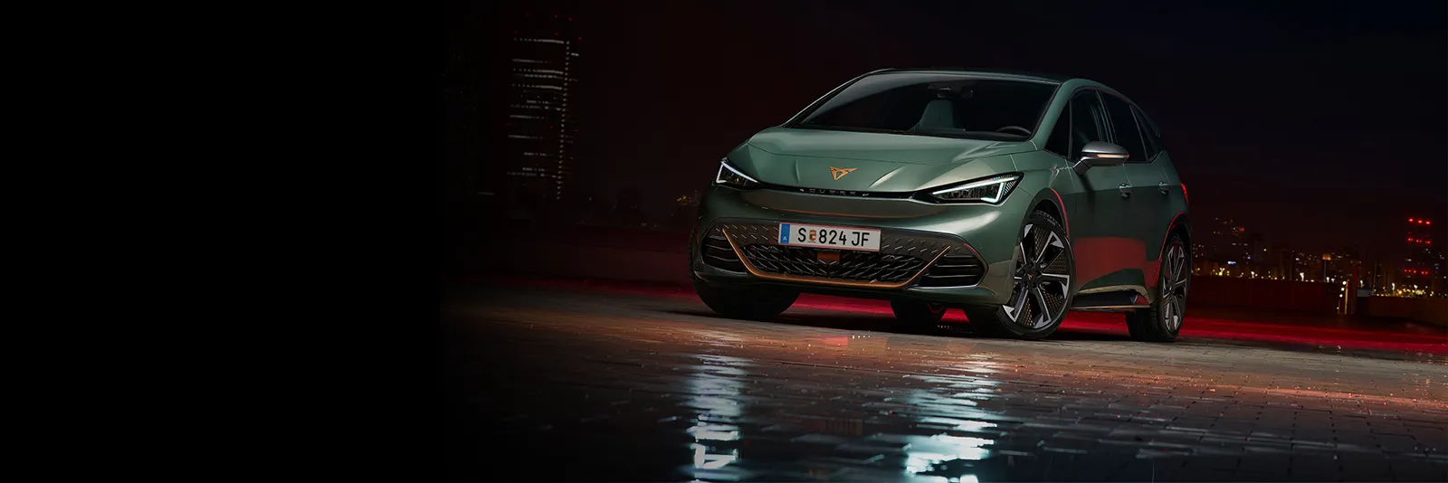 Der CUPRA Born VZ in Grün steht vor dunklem City Hintergrund. 