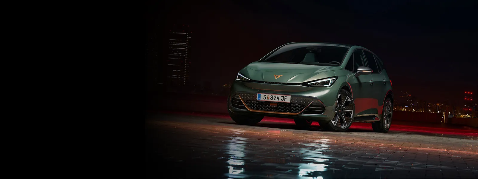 Der CUPRA Born VZ in Grün steht vor dunklem City Hintergrund. 